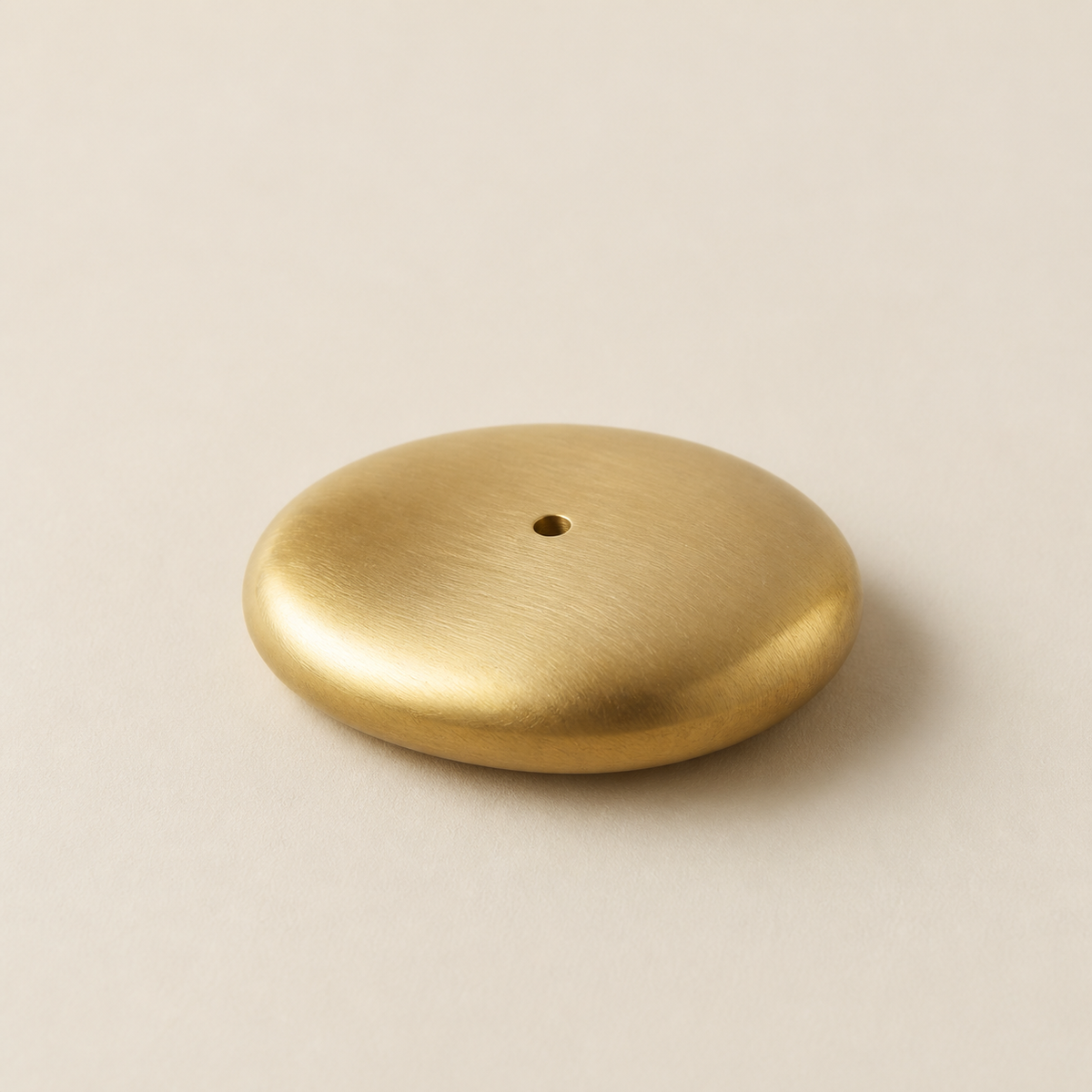 Minimal brushed brass incense rest in a pebble-like shape