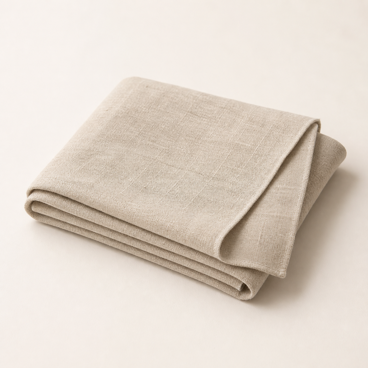 Folded natural oatmeal linen table runner on an off-white background