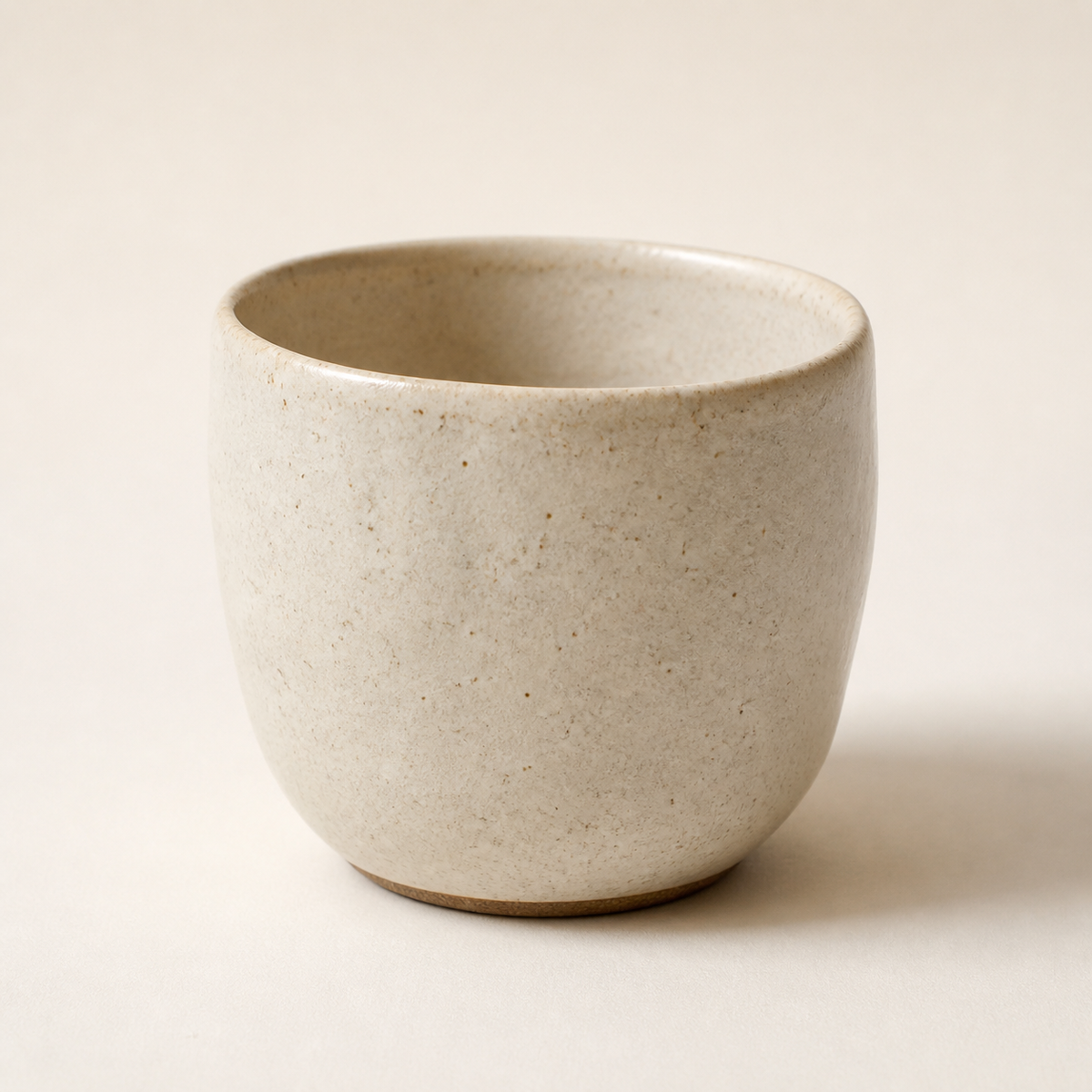Warm ivory handmade stoneware cup on an off-white background